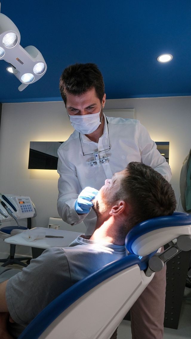 Dentist examining a patient in a modern dental office with overhead lighting.